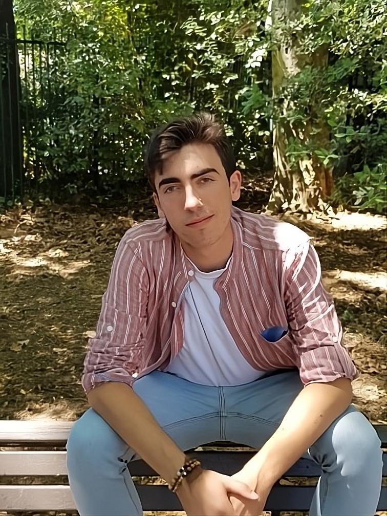 Un homme d'une vingtaine d'année se tient sur un banc.